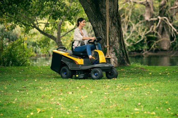 Person mäht Rasen mit Rasenmähertraktor